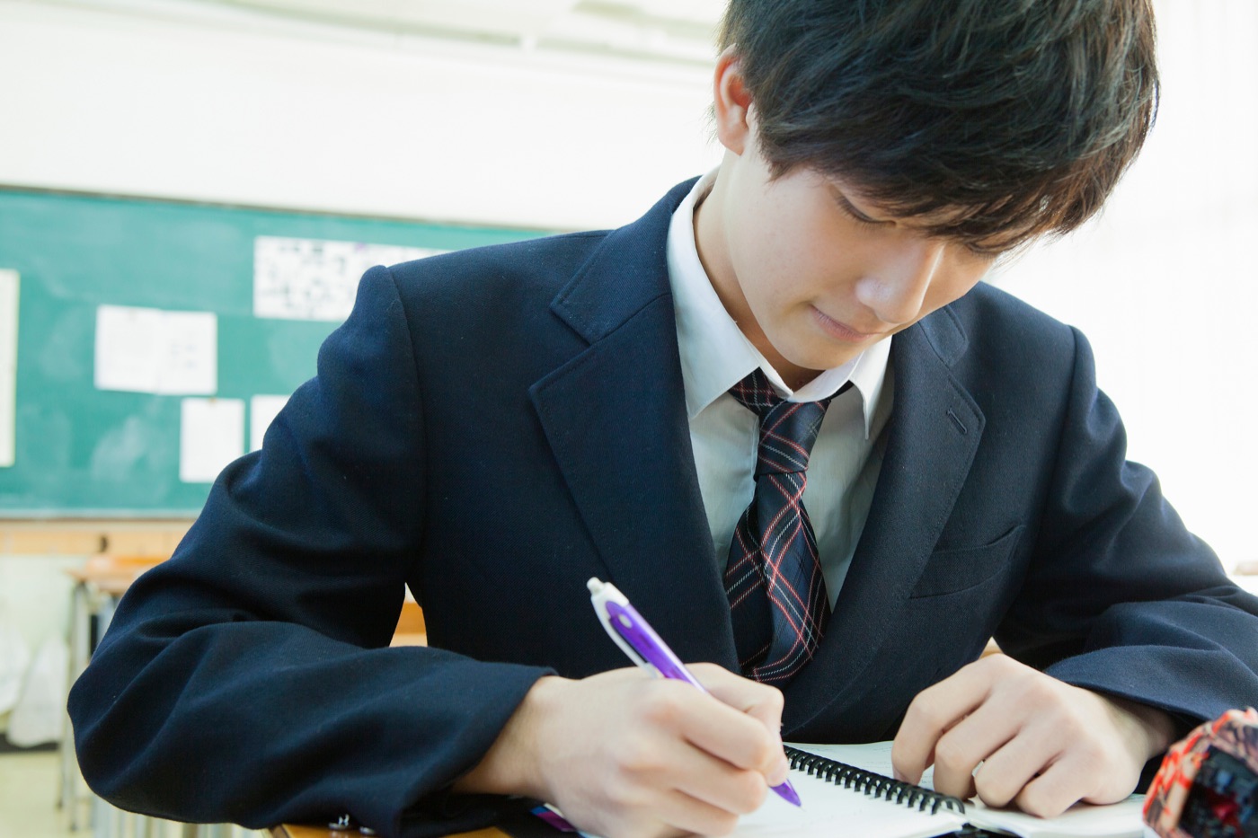 制服を着て教室で学ぶ高校生