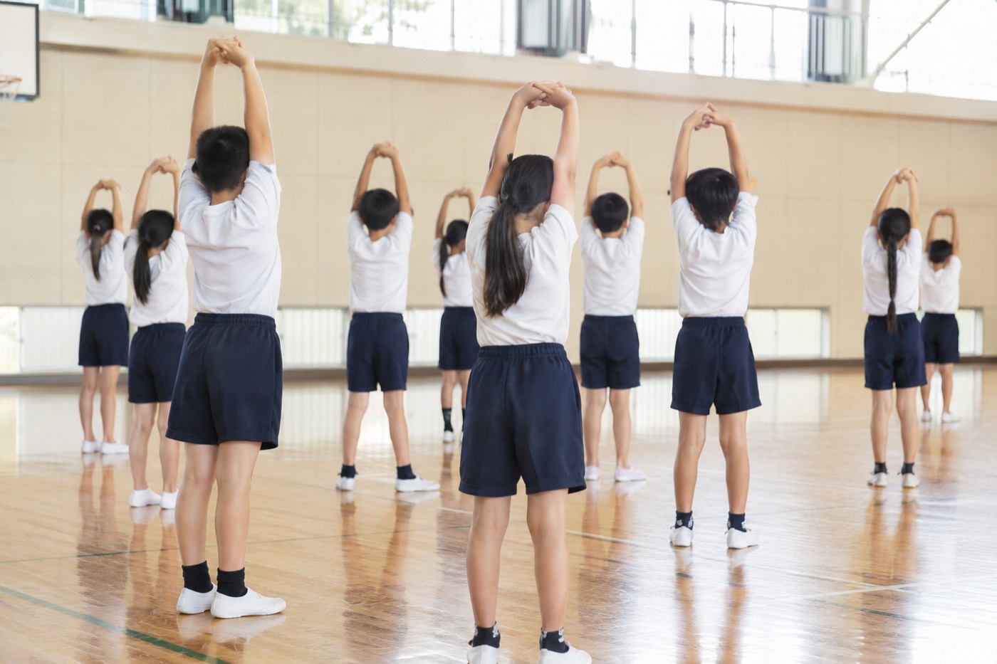 体育館で準備体操をする小学生たち