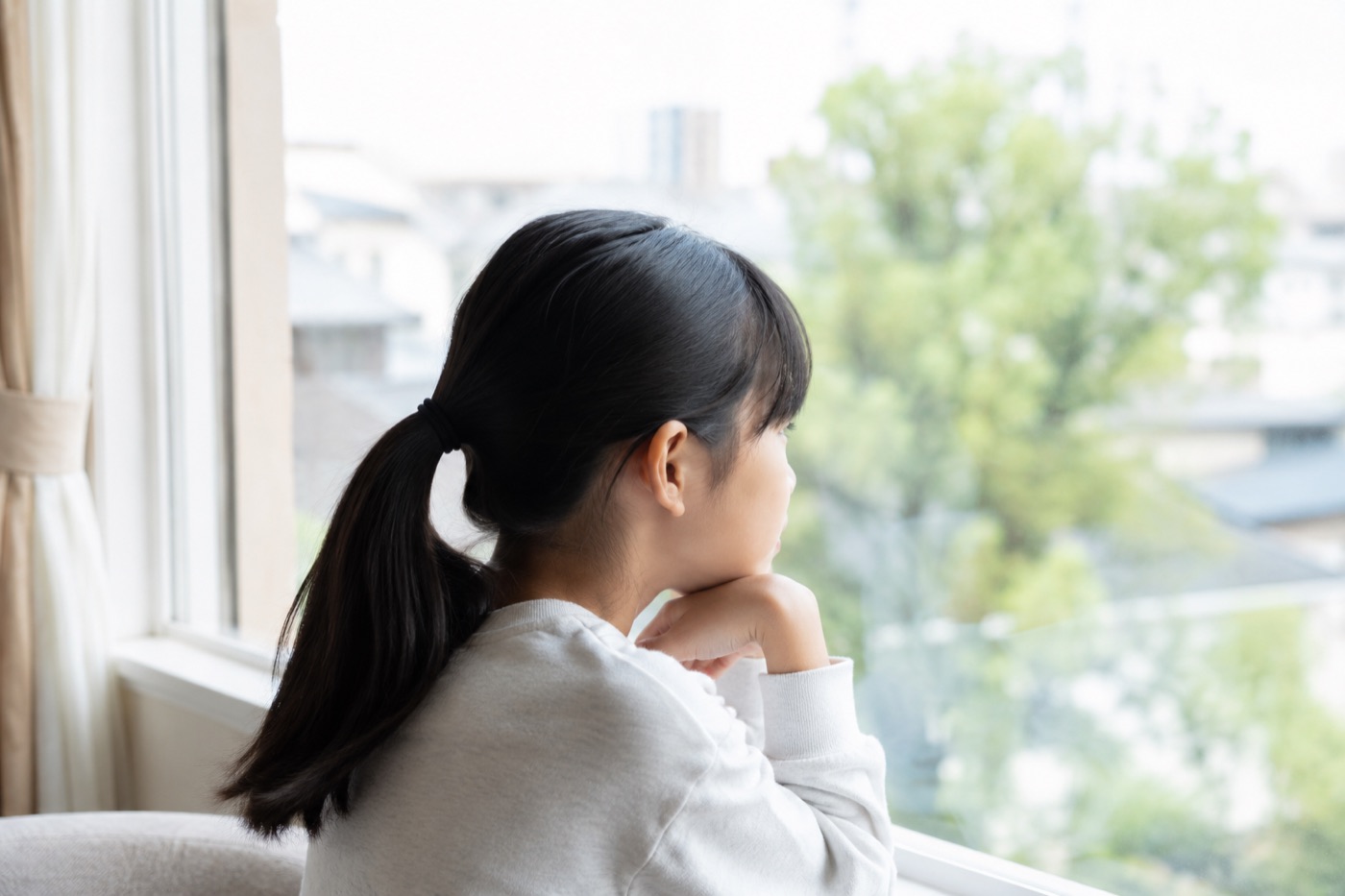 窓の外を眺めながら物思いにふける子供
